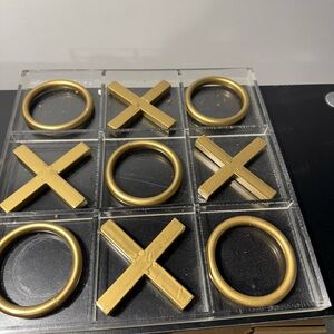 Tic Tac toe board with gold pieces and a acrylic case